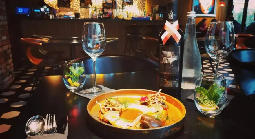Elegancka kolacja w Nowym Targu. Na stole danie, wino i woda. Idealne miejsce, by dowiedzieć się, gdzie zjeść w Nowym Targu.