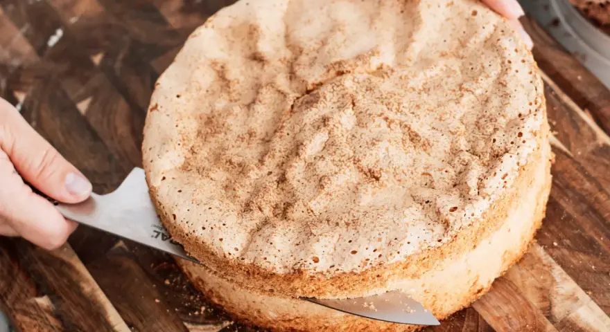 En person skär en fluffig sockerkaksbotten med en kniv. Perfekt för ditt nästa cake recept!