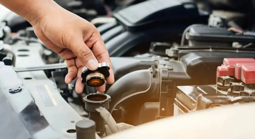 Hand removing radiator cap. This image might be relevant when researching radiator hose replacement cost.