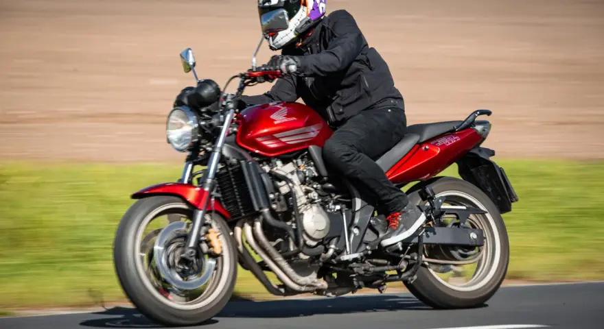 Motocyklista w kasku w stylu Jokera pędzi na czerwonym Honda CBF 600. Dane techniczne tego modelu są imponujące.