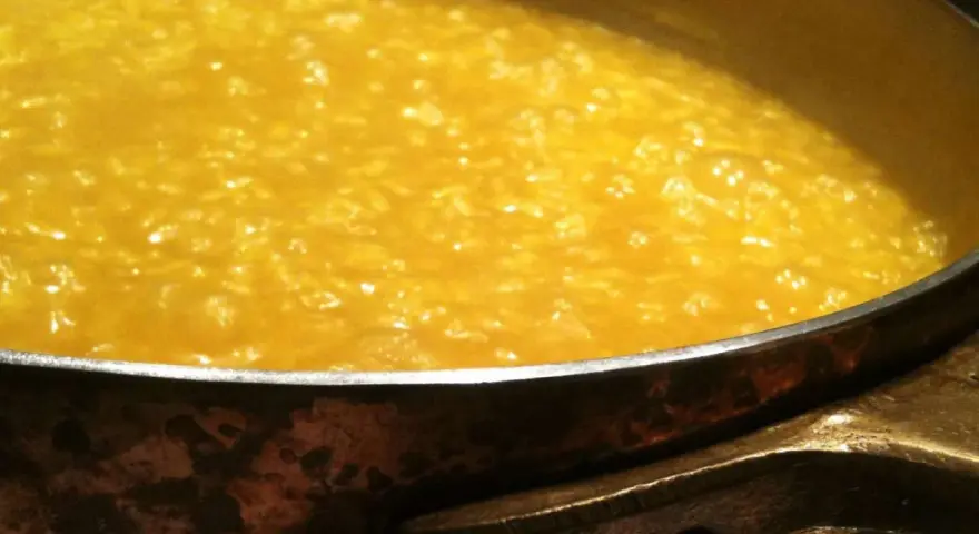 Un cremoso risotto alla milanese che sobbolle in una pentola di rame, pronto per essere gustato.
