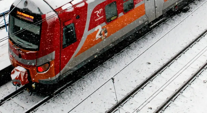 Czerwono-szary pociąg Polregio na zaśnieżonych torach.