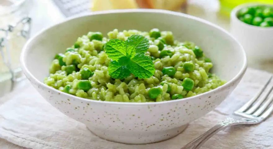 Un cremoso risotto con piselli, guarnito con menta fresca. Un piatto primaverile che celebra il gusto del riso e piselli.