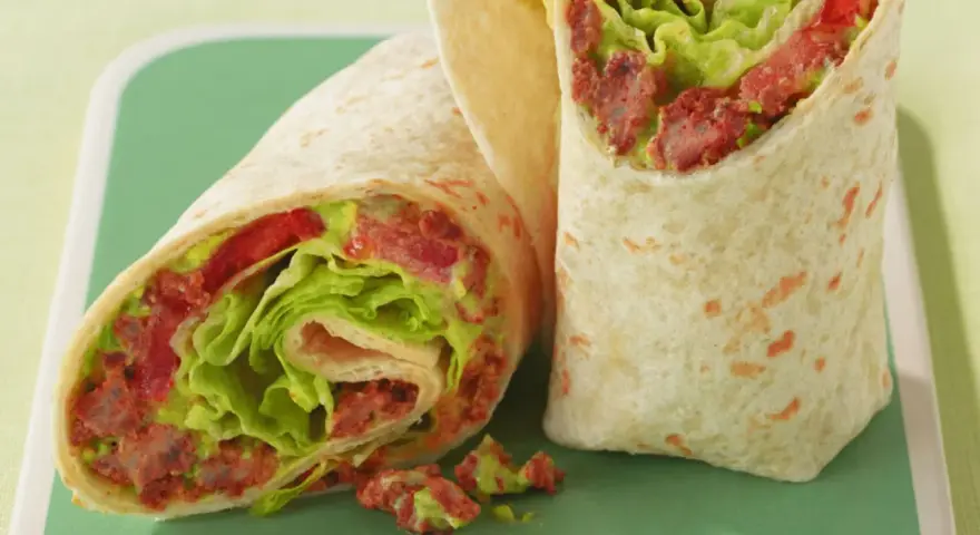 Zwei saftige wraps zum mitnehmen, gefüllt mit knackigem Salat, Tomaten und einer würzigen Fleischfüllung. Perfekt für unterwegs!