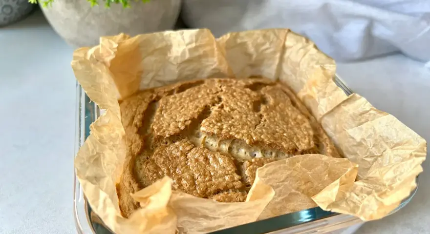 Świeżo upieczony chleb keto w papierze do pieczenia, z chrupiącą skórką i puszystym wnętrzem. Idealny na śniadanie.