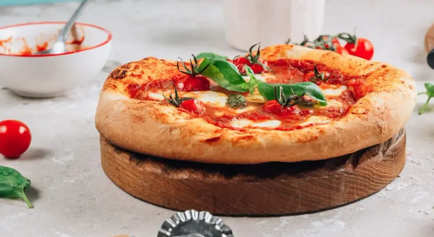 Pyszna pizza na drewnianej desce, gotowa do pokrojenia. Idealna na to, na czym piec pizze.