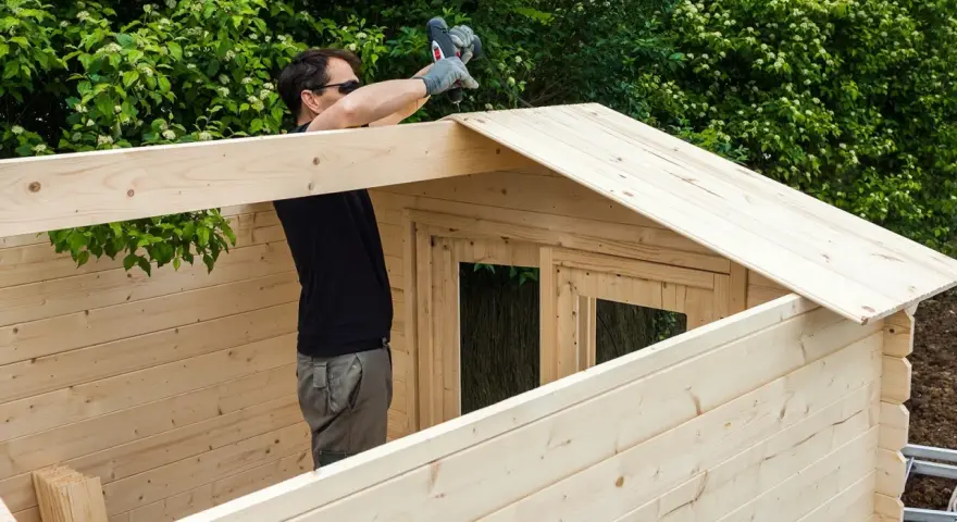 Hombre montando una caseta de madera. La madera clara y resistente es la mejor madera para exterior.