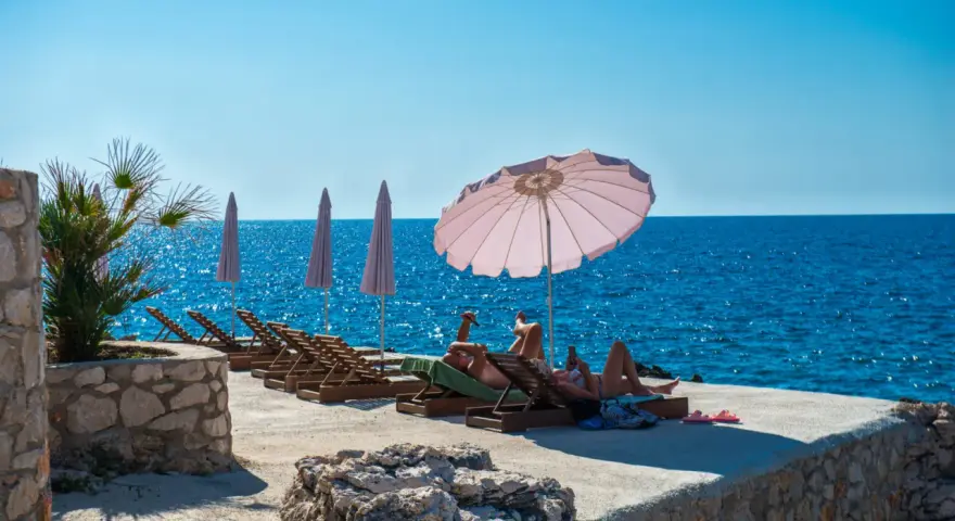Słoneczna plaża w Czarnogórze, na co uważać? Leżaki, parasole i turkusowe morze. Idealne miejsce na relaks, ale pamiętaj o kremie z filtrem!