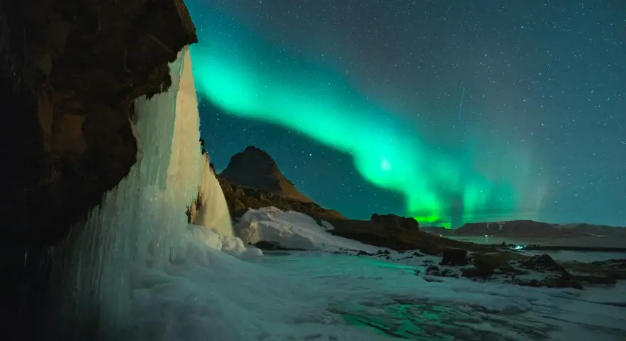 Lodowy wodospad i zorza polarna na nocnym niebie. Islandia w styczniu, magiczny widok.
