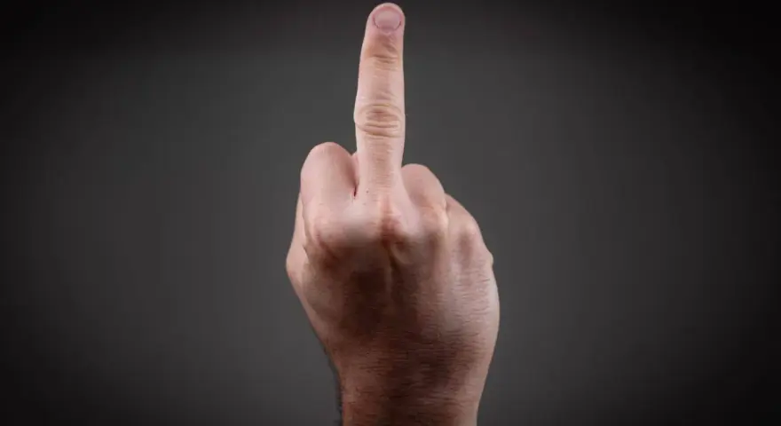 Eine Hand zeigt den Mittelfinger. Dies kann als Geste der Ablehnung oder als Zeichen der Rebellion gesehen werden, die eine Strafe nach sich ziehen kann.
