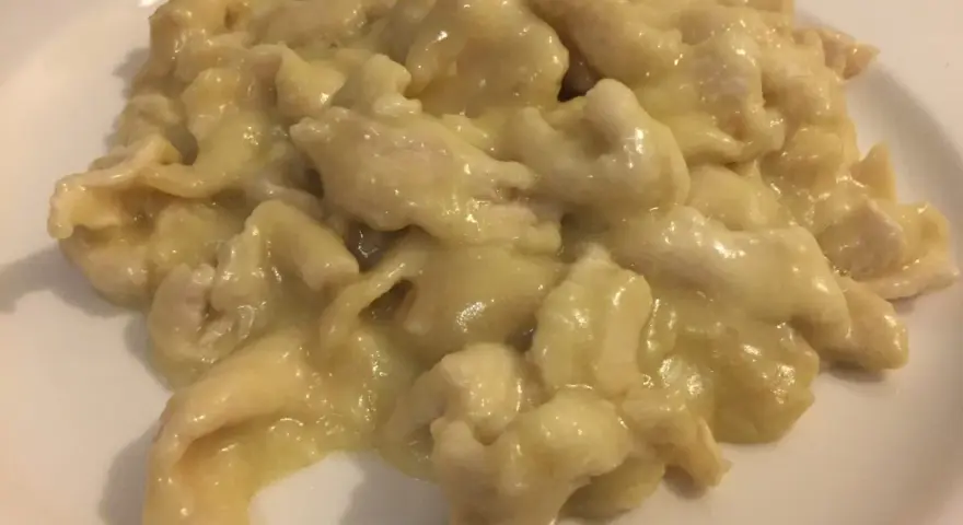 Straccetti di pollo al limone, un piatto cremoso e saporito, servito su un piatto bianco.