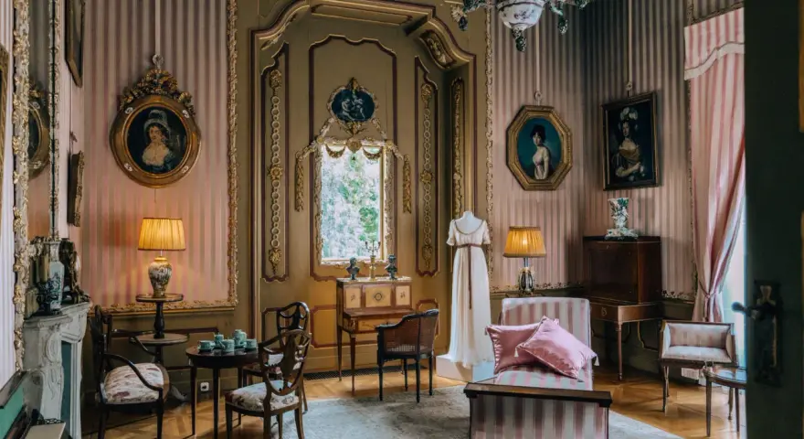 Eleganckie wnętrze, być może pałac Radziwiłłów, z portretami dam, manekinem w sukni i meblami w stylu epoki.