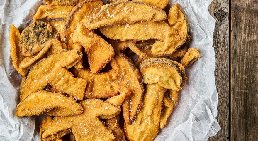 Un cesto pieno di croccanti funghi fritti, cosparsi di sale grosso, pronti per essere gustati.