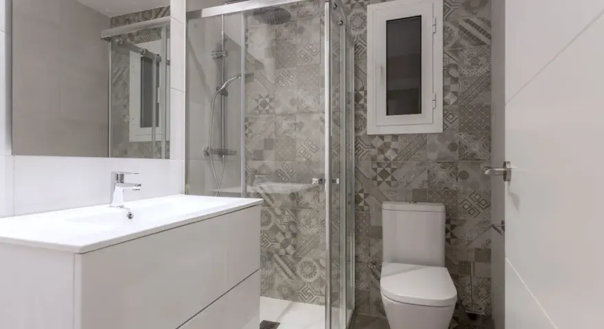 Salle de bain moderne avec douche vitrée, lavabo suspendu et carrelage graphique. Un projet pour agrandir salle de bain avec style.
