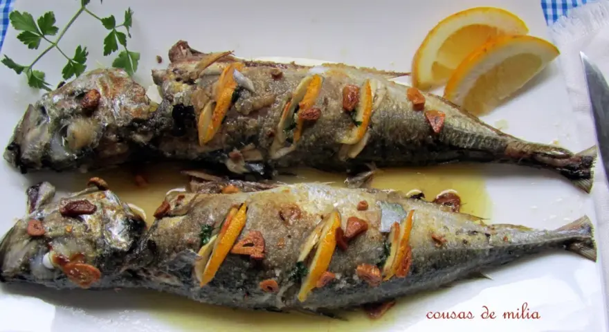 Dos jureles al horno, dorados y jugosos, con rodajas de limón y ajo. Un plato sencillo y delicioso.