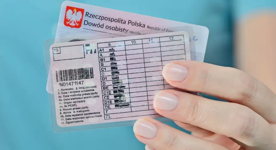 Polskie prawo jazdy z kategorią B, obok dowodu osobistego. Dłoń z zadbanymi paznokciami trzyma dokumenty.
