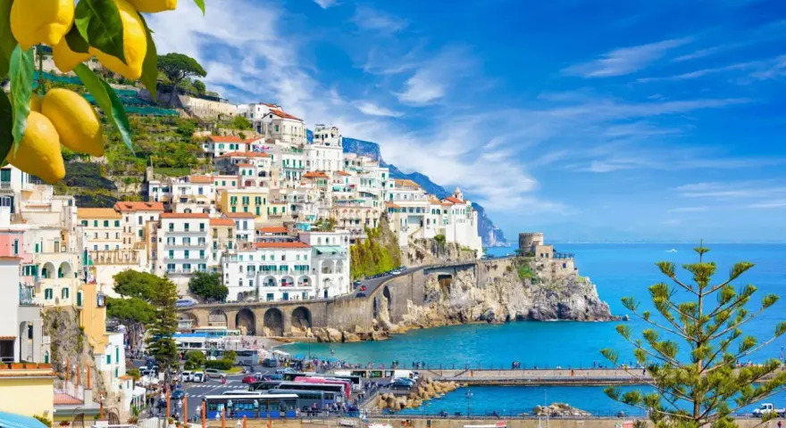 Costiera Amalfitana, un sogno di **Italia in moto** tra limoni e mare blu. Case bianche aggrappate alla roccia, un borgo pittoresco.