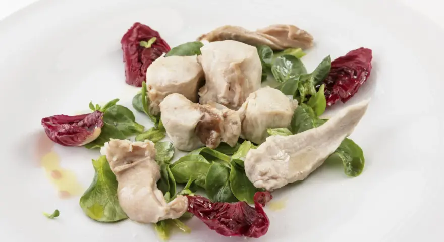 Delicato tonno di coniglio servito con insalata fresca e radicchio croccante, condito con olio d'oliva.