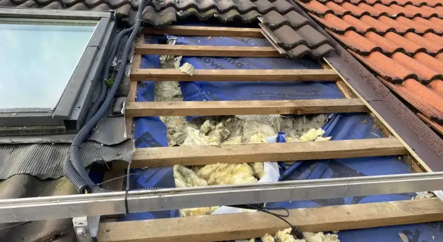 Uszkodzony dach z widoczną izolacją, jakby kuna zrobiła sobie tam gniazdo.