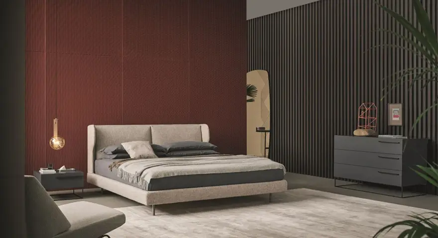 Habitación moderna con pared texturizada en rojo terracota, cama beige y cómoda gris. Inspírate para como pintar una habitacion.