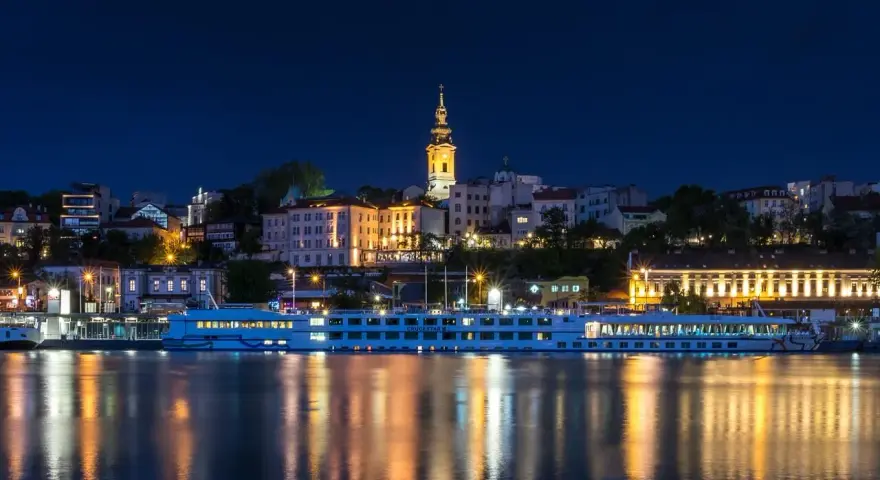 Nocny Belgrad z rzeką i statkiem wycieczkowym. Czy do Serbii potrzebny jest paszport? Sprawdź przed podróżą!