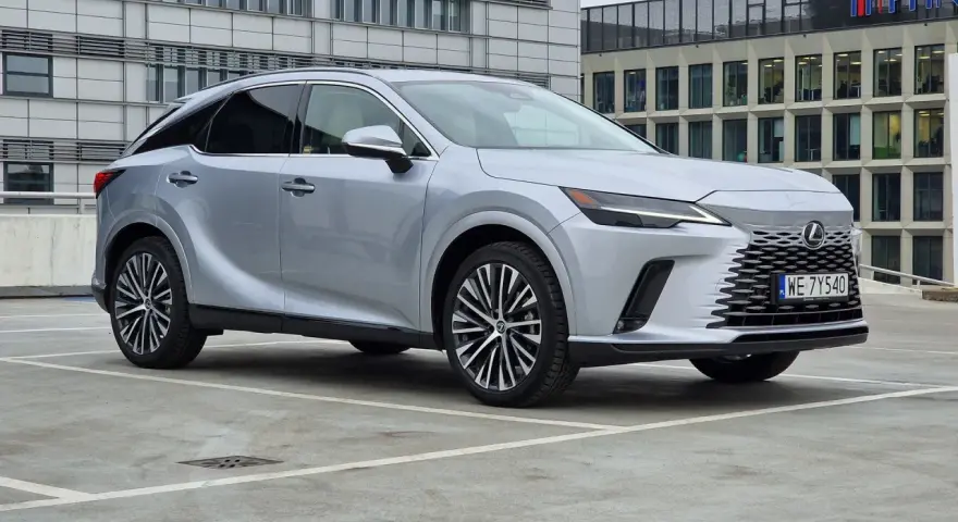 Srebrny Lexus RX 350h zaparkowany przed nowoczesnym budynkiem biurowym.