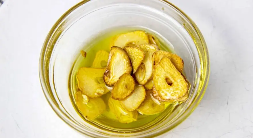 Ajo laminado y dorado en aceite de oliva, listo para añadir sabor a tu rape a la plancha.