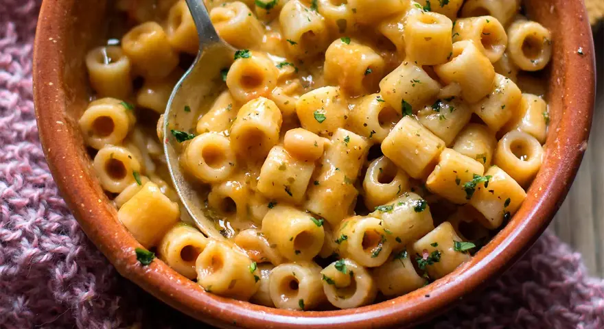 Un piatto fumante di pasta e fagioli, con ditalini e fagioli borlotti in un sugo cremoso, guarnito con prezzemolo tritato.