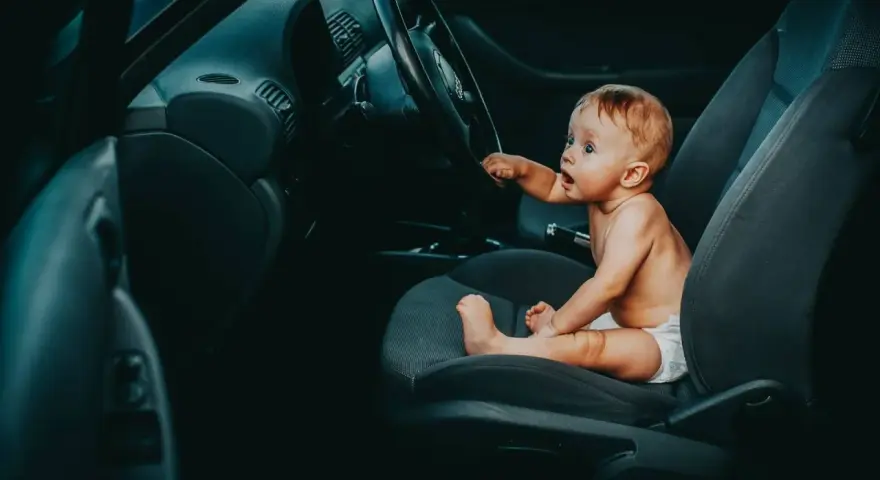 Maluch siedzi za kierownicą, jakby zastanawiał się, od kiedy dziecko może jeździć z przodu.