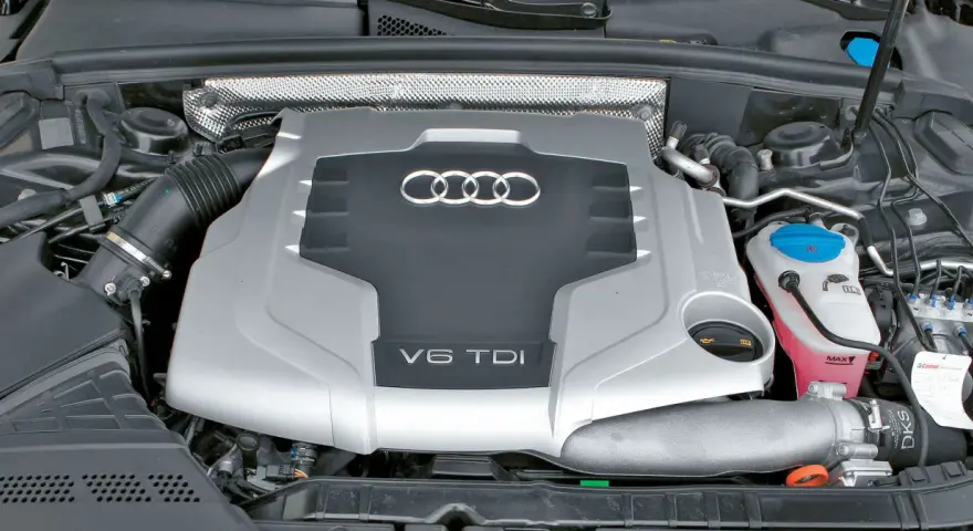 Silnik V6 TDI Audi z widocznym logo i oznaczeniem pojemności. Widać elementy układu dolotowego i płyny eksploatacyjne.