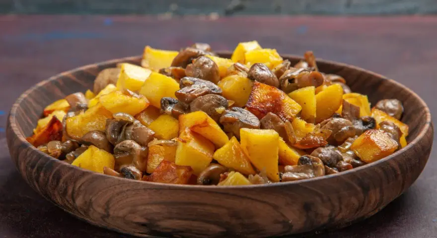 Un delicioso salteado de setas y patatas doradas en un cuenco de madera.