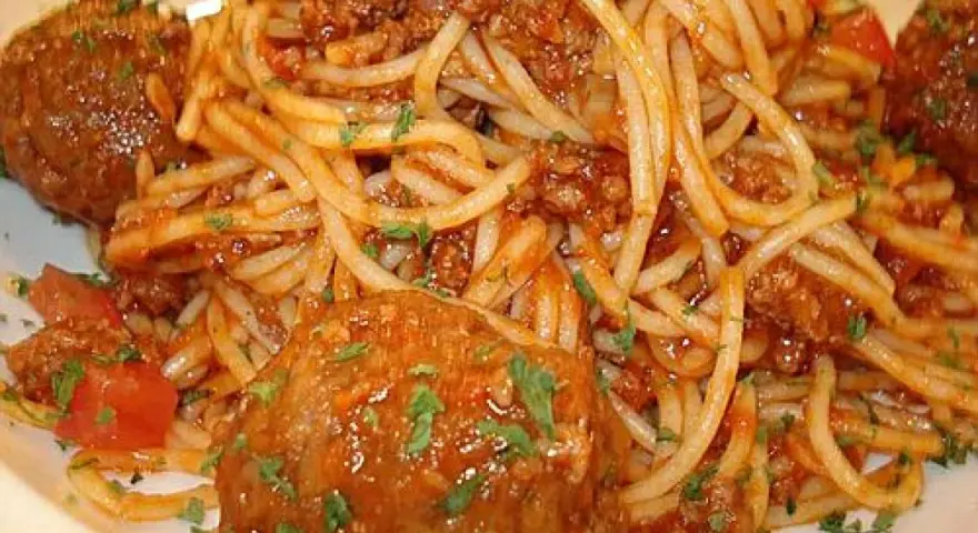 Pyszne spaghetti z pulpetami w sosie pomidorowym, posypane natką pietruszki. Klasyczne danie, które zawsze smakuje wyśmienicie.
