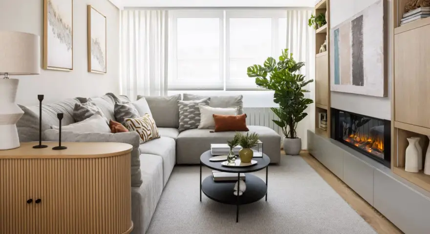 Sofá gris, mesa de centro negra, chimenea moderna y mueble de madera. Una sala acogedora, perfecta para una reforma sin obras.