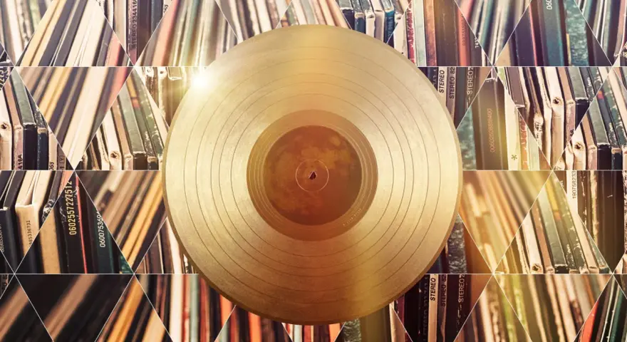 Złota płyta winylowa na tle stosów albumów. Czy to symbol tego, kto sprzedał najwięcej płyt w historii?