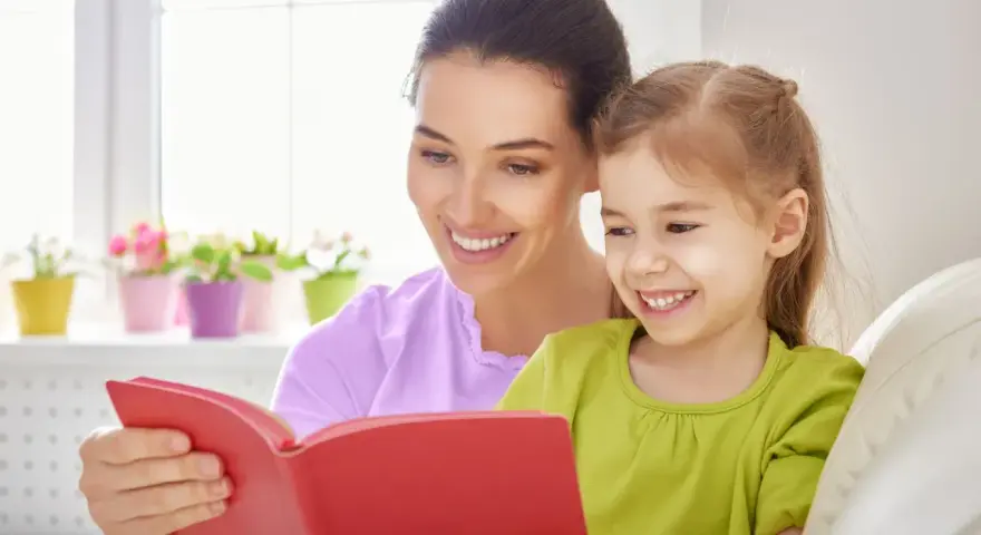 Uśmiechnięta mama czyta bajkę córce. To wspaniała opieka na dziecko 2 dni w tygodniu, pełna radości i wspólnych chwil.
