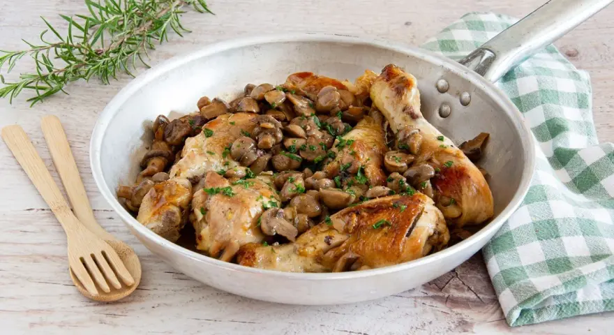Delizioso pollo con funghi in padella, guarnito con prezzemolo fresco e accompagnato da rosmarino.
