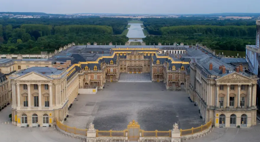 Le château de Versailles, construit par Louis XIV, s'étend majestueusement avec ses cours pavées et ses jardins.