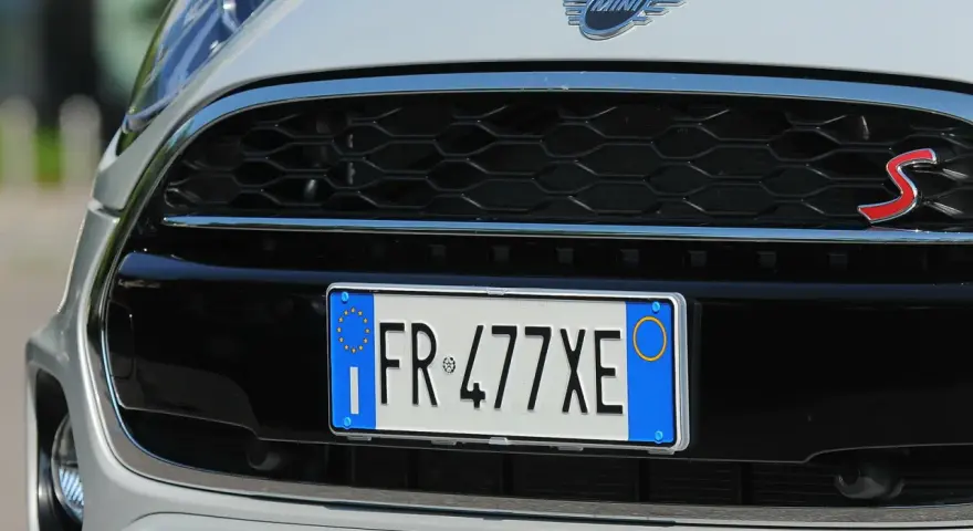 Targa di immatricolazione auto estera su una Mini Cooper S bianca.
