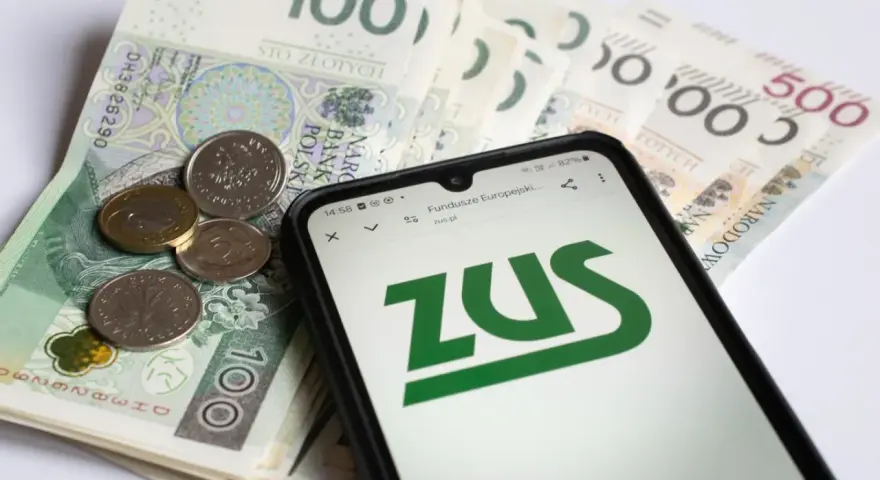 Złotówki i monety obok telefonu z logo ZUS. Może to być związane z wnioskiem o zasiłek opiekuńczy.