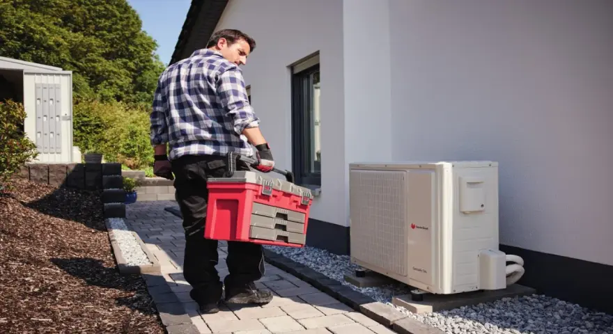 Technik z walizką narzędziową przy pompie ciepła. Może sprawdzać kody błędów urządzenia.