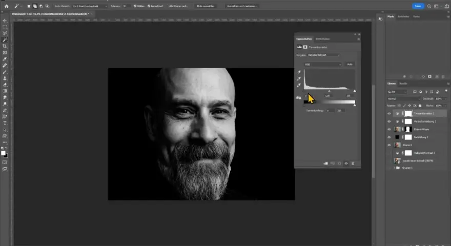 Portret mężczyzny w czerni i bieli z widocznym panelem korekty tonalnej w Photoshopie.