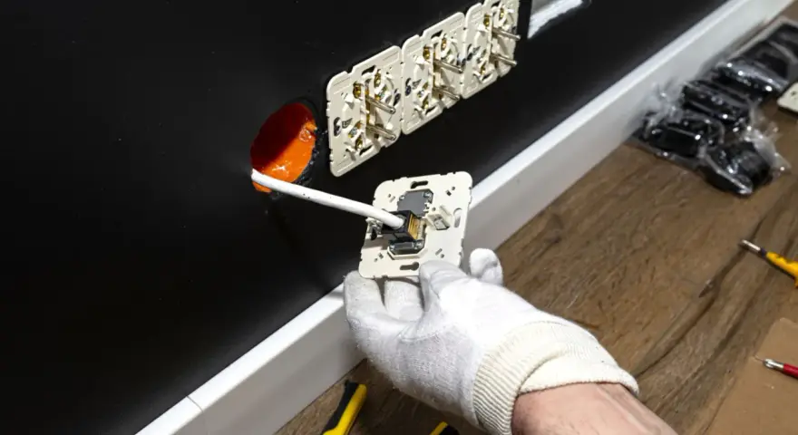 Instalator montuje gniazdko elektryczne. Zastanawiasz się, ile za punkt elektryczny? Widać tu kilka gotowych do podłączenia gniazdek.