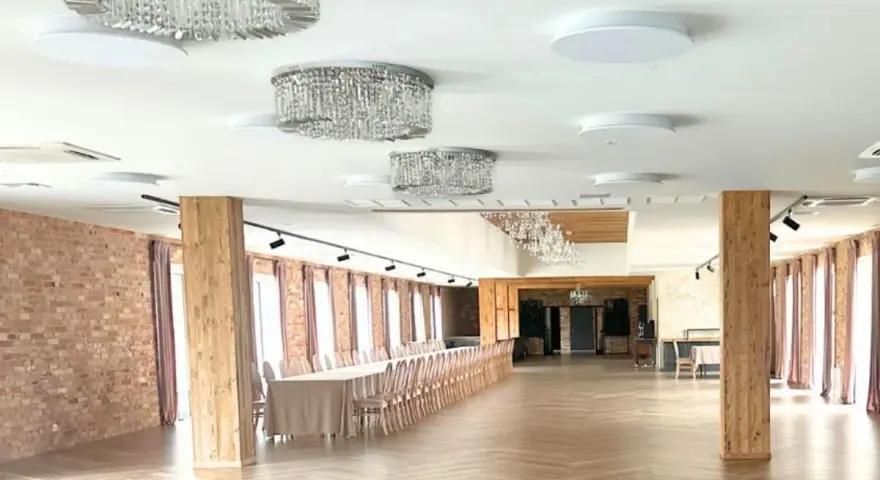 Elegancka sala weselna z kryształowymi żyrandolami i długimi stołami. Zastanawiasz się, ile kosztuje wesele na 120 osób w takim miejscu?