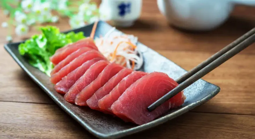 Vackert upplagd tonfisk sashimi på en tallrik, redo att avnjutas med en god vin.