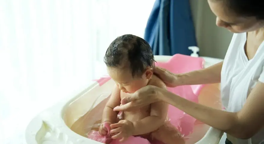 Matka kąpie dziecko w wanience.
