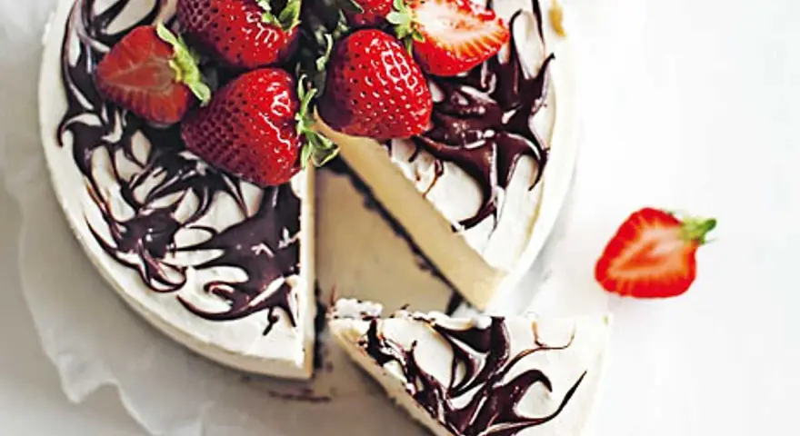 En krämig no bake cheesecake med chokladdrizzle och färska jordgubbar. En bit är uppskuren.