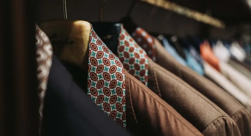 Un guardaroba elegante con giacche marroni e camicie dal tessuto dalle tinte diverse e vivaci, con fantasie geometriche.