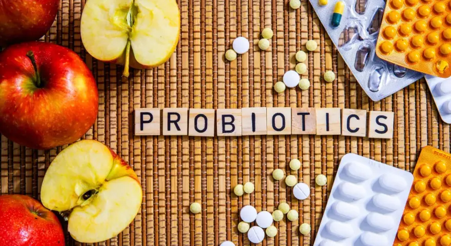 Äpfel und Pillen umgeben das Wort "PROBIOTICS". Eine natürliche Methode, probiotika gegen akne zu finden.