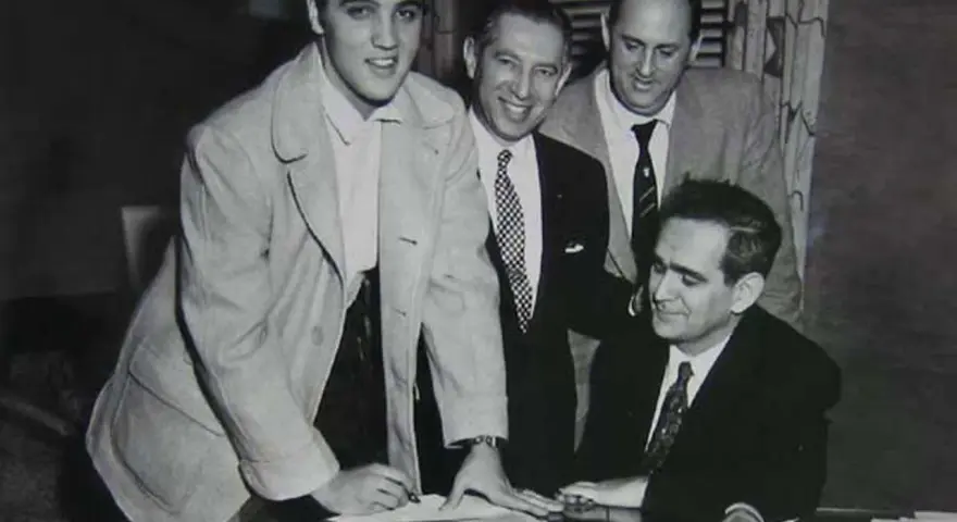 Elvis Presley unterschreibt Dokumente, ein wichtiger Schritt für seinen späteren Elvis Presley net worth.