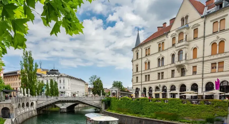 Lublana co zobaczyć: malowniczy widok na rzekę Ljubljanicę, most i zabytkowe budynki. Rejs statkiem to świetny sposób na zwiedzanie.